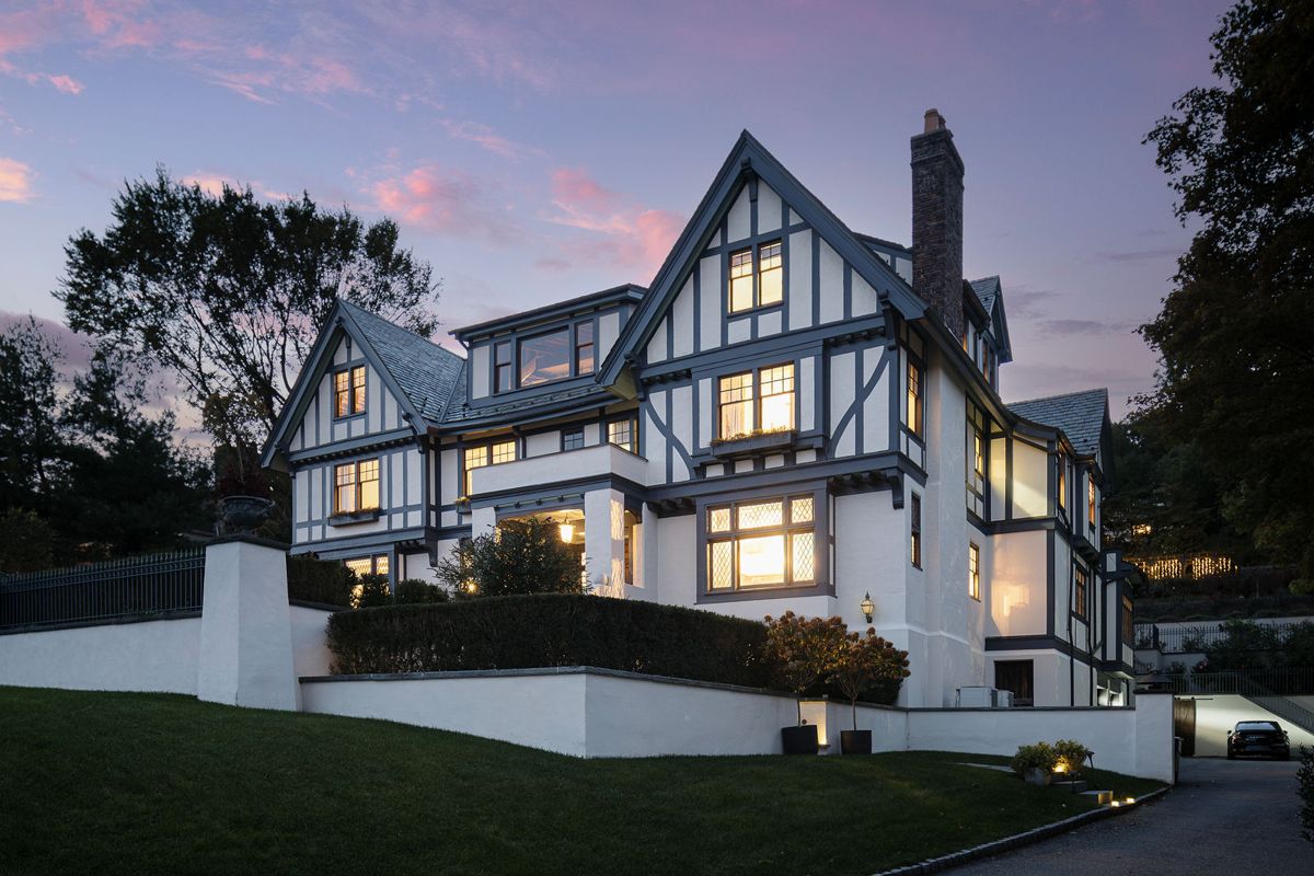 The Tudor Revival front elevation of 184 Upper Mountain Avenue, Montclair, illuminated at dusk